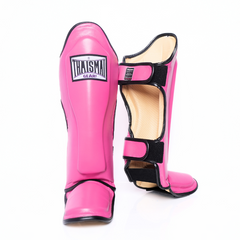 A pair of pink shin guards with black trim and a beige interior lining, shown on a clean white background. One shin guard displays a white brand label that reads 'THAISAI THAI SHAI'.