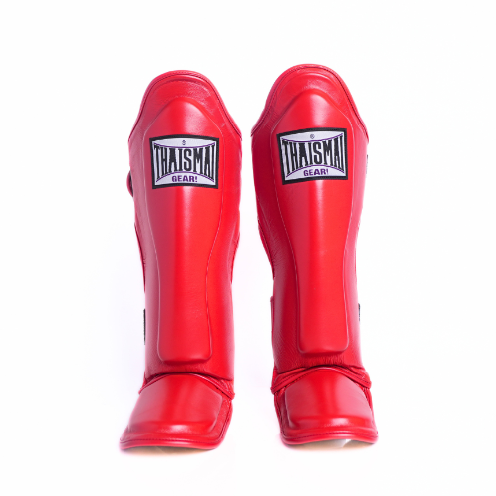 A pair of red shin guards with black and white 'THAISMAN GLARE' brand patches, shown from a front-facing perspective on a solid white background.