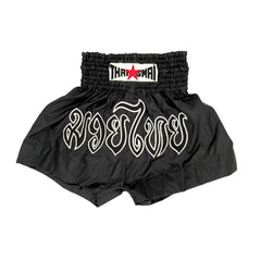 Black Muay Thai shorts with branding on a white background