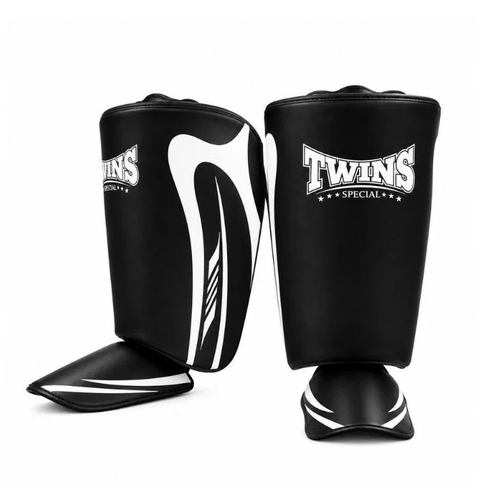 A pair of black shin guards with white graphic accents and the 'Twins Special' logo, displayed on a clean white background.