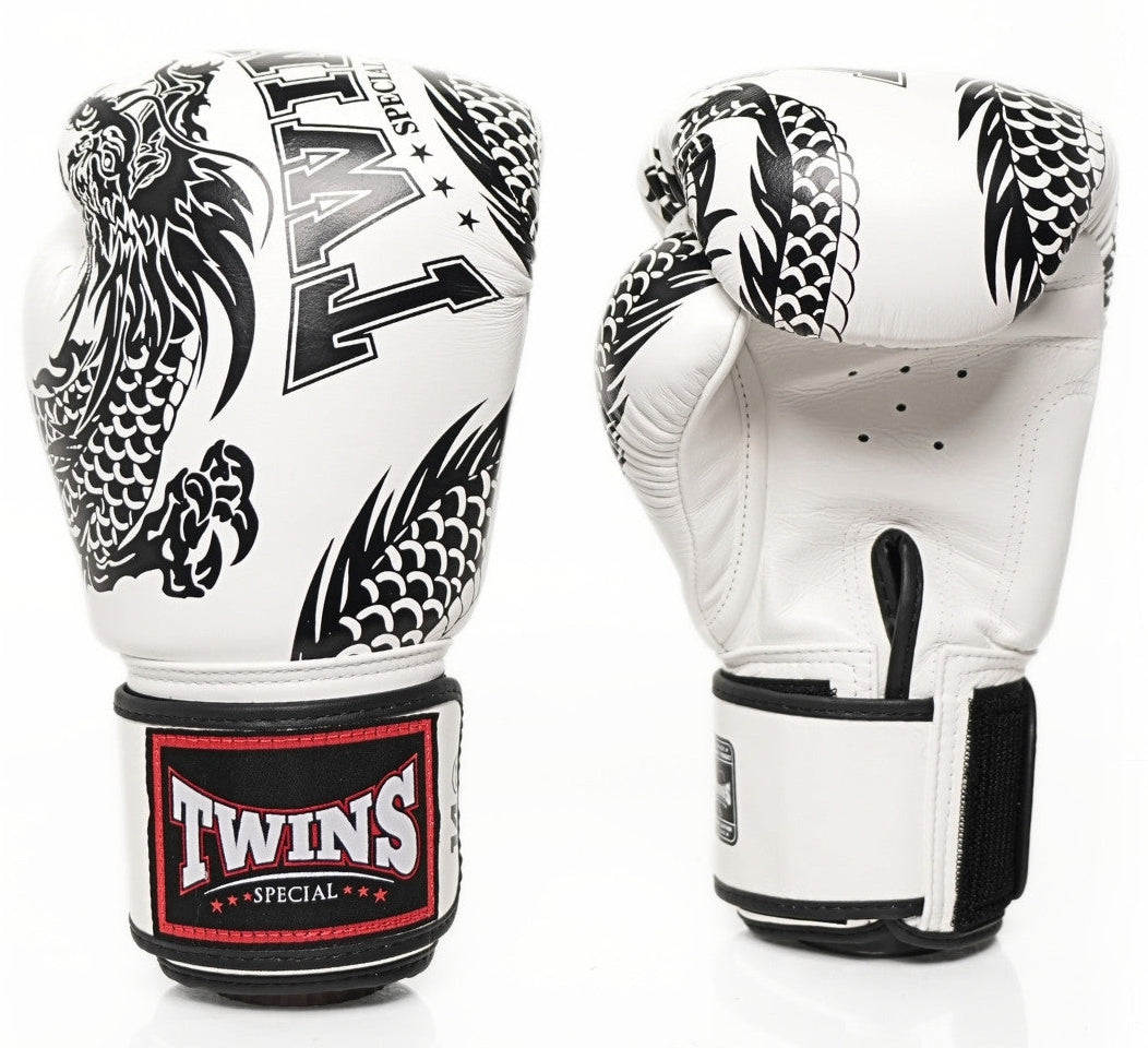 A pair of Twins Special boxing gloves shown from the front and back on a white background. The gloves are primarily white with black dragon illustrations and a black wrist strap featuring a red and white Twins logo patch.